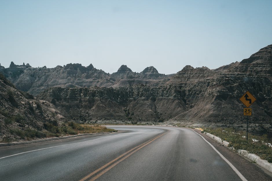 Winding road through a rocky valley under clear skies, perfect for travel themes.
