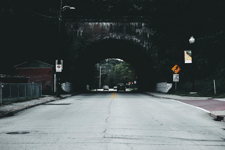 A quiet urban road leading through a tunnel with visible traffic and speed signs.